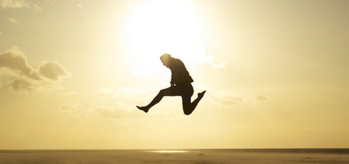 Silhouette of a figure jumping on a beach at sunset
